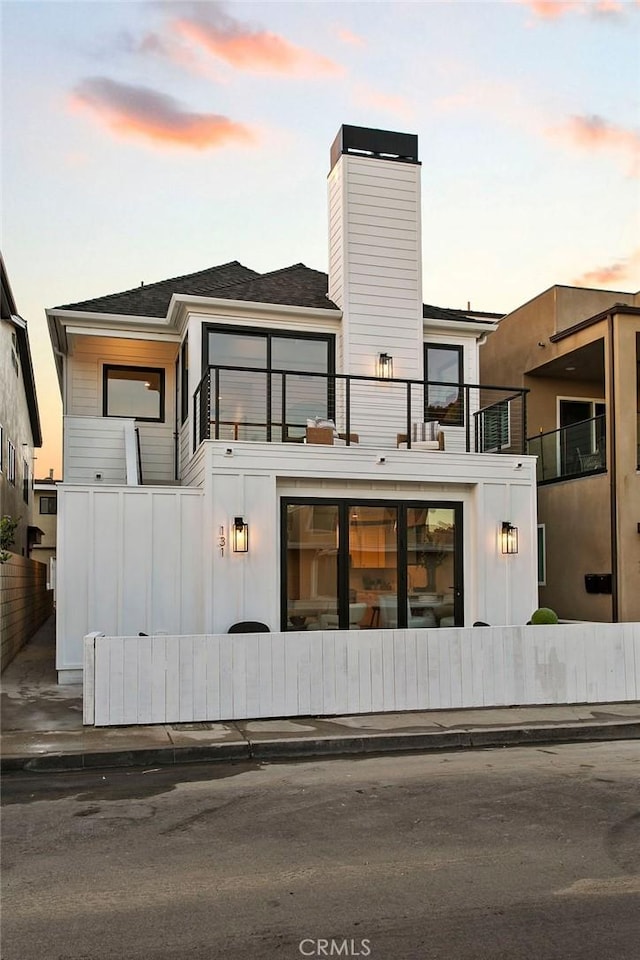 back house at dusk featuring a balcony