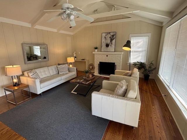 living room featuring ceiling fan, lofted ceiling with beams, dark hardwood / wood-style flooring, and a brick fireplace