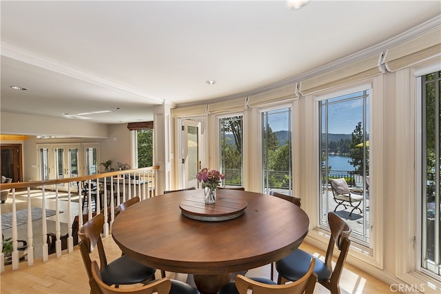 dining room featuring a water view, light wood-type flooring, and crown molding