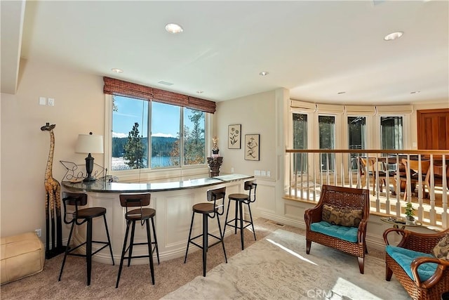 kitchen featuring a water view, a breakfast bar, and light carpet