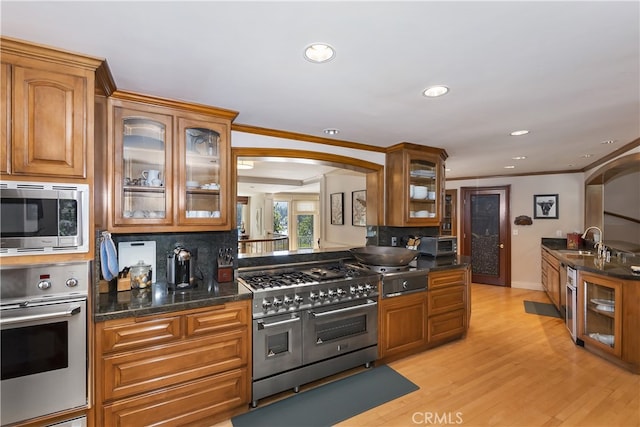 kitchen with tasteful backsplash, light hardwood / wood-style floors, sink, crown molding, and appliances with stainless steel finishes