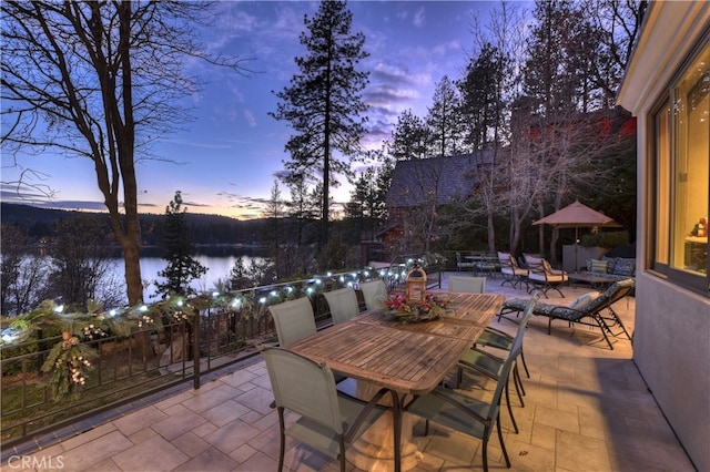 patio terrace at dusk featuring a water view