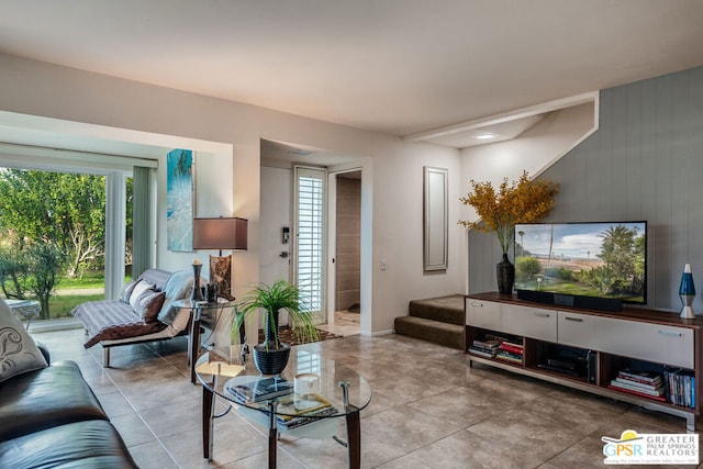 tiled living room featuring wood walls