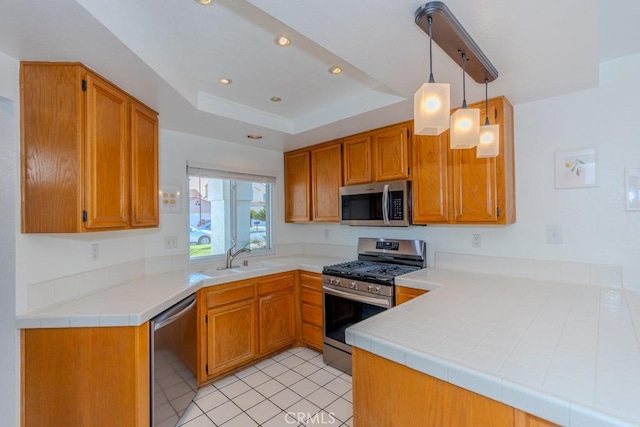 kitchen featuring sink, a raised ceiling, kitchen peninsula, decorative light fixtures, and appliances with stainless steel finishes