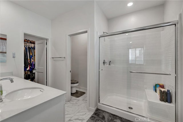 bathroom featuring vanity, a shower with shower door, and toilet