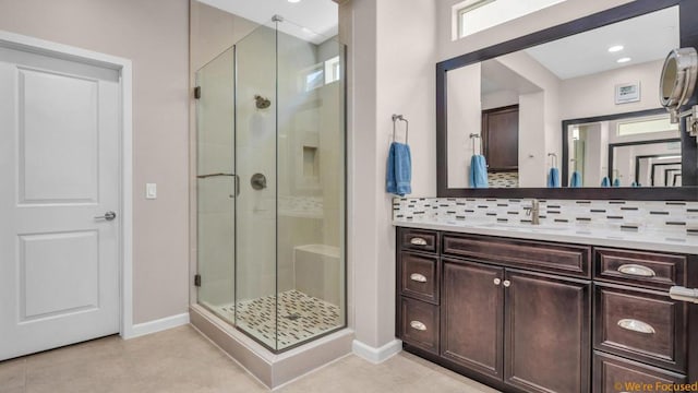 bathroom featuring tile patterned floors, decorative backsplash, a shower with door, and vanity