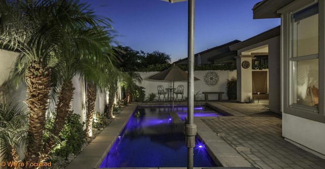 pool at dusk with a patio area