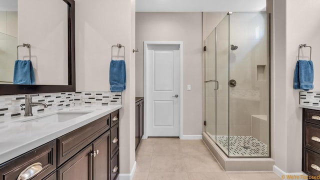 bathroom with tile patterned flooring, decorative backsplash, a shower with door, and vanity