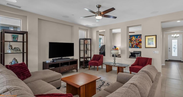 tiled living room featuring ceiling fan with notable chandelier