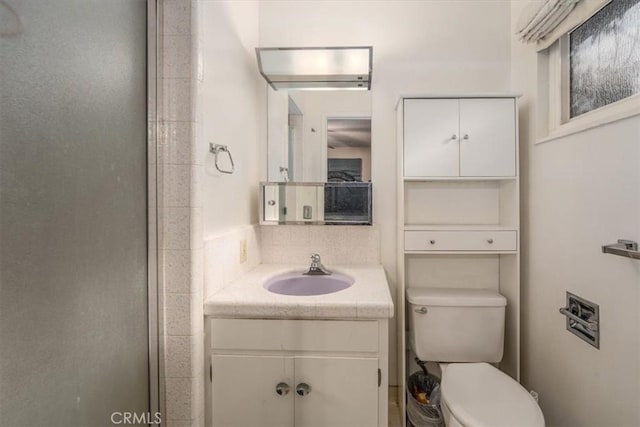 bathroom with vanity, toilet, and a shower with shower door