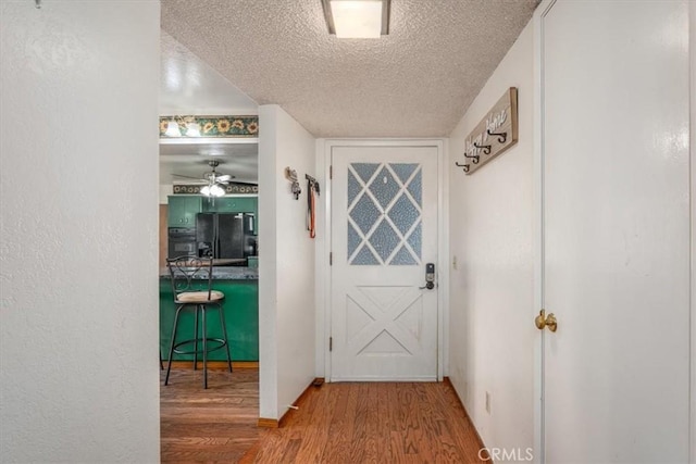 doorway featuring a textured ceiling, hardwood / wood-style flooring, and ceiling fan