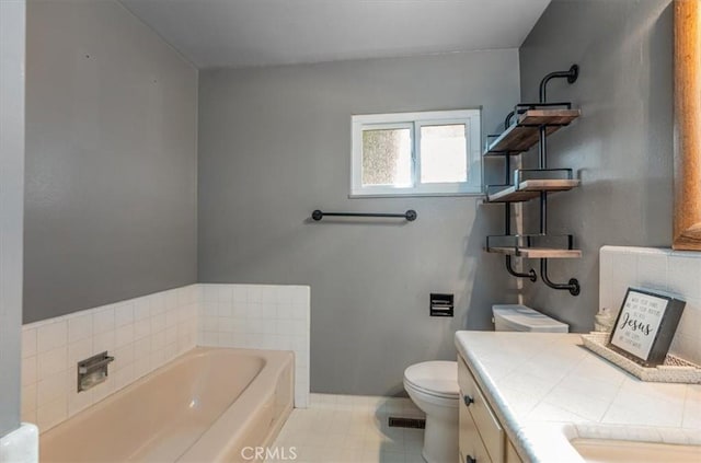 bathroom with a washtub, vanity, tile patterned flooring, and toilet