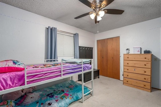 carpeted bedroom featuring ceiling fan, a closet, and a textured ceiling