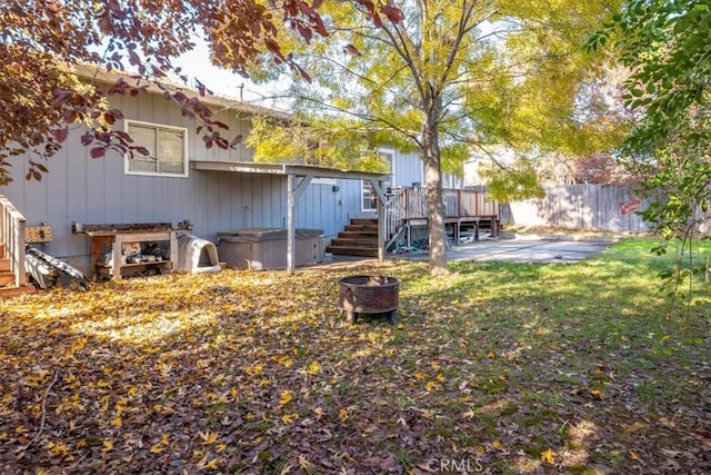 rear view of property featuring a lawn, a deck, a patio, and a hot tub