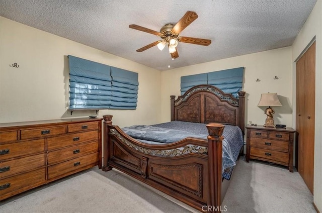 bedroom featuring ceiling fan, a textured ceiling, light carpet, and a closet