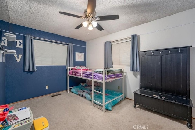 bedroom featuring ceiling fan, carpet, and a textured ceiling