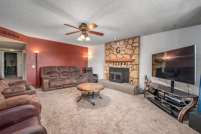 carpeted living room featuring a textured ceiling, a wood stove, and ceiling fan