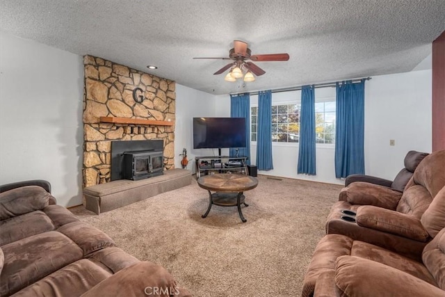 living room featuring a wood stove, carpet, and a textured ceiling