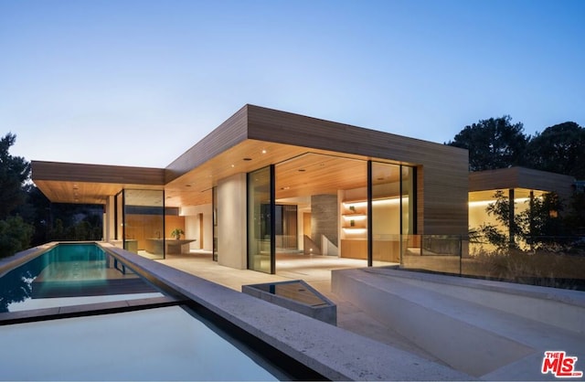 pool at dusk featuring a patio area