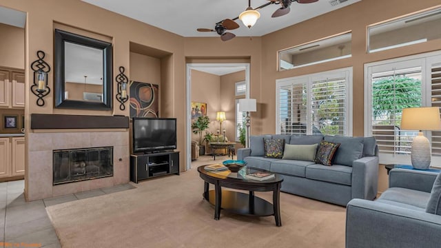 carpeted living room with ceiling fan and a tiled fireplace