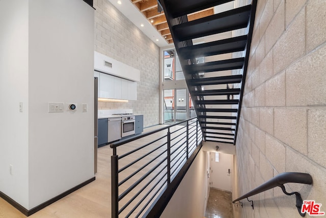 stairway with hardwood / wood-style floors and a high ceiling