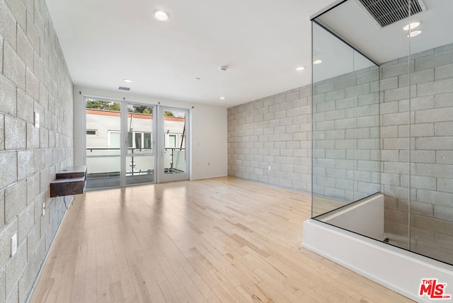 unfurnished living room with light hardwood / wood-style flooring and tile walls