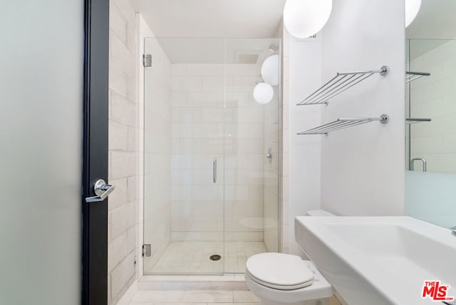 bathroom featuring tile patterned flooring, toilet, a shower with door, and sink