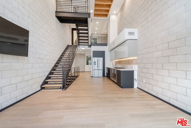 staircase with hardwood / wood-style floors, sink, and a high ceiling