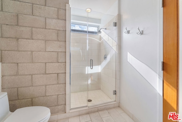 bathroom featuring toilet and a shower with door