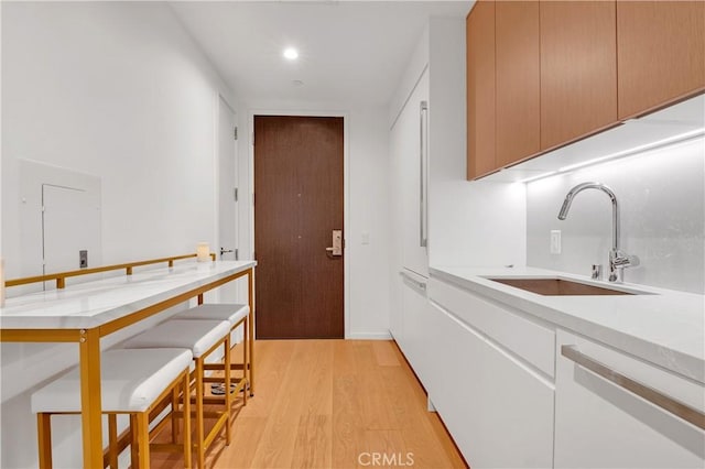 kitchen with sink, white dishwasher, and light hardwood / wood-style floors