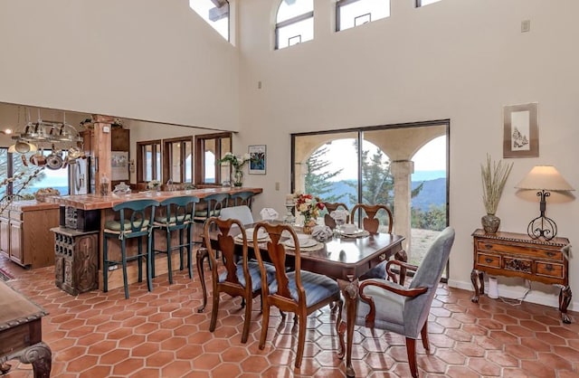 dining area with tile patterned flooring, a high ceiling, and a healthy amount of sunlight