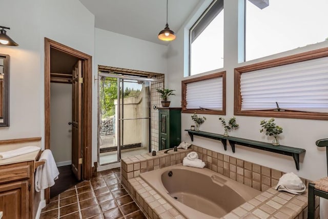 bathroom featuring vanity, a relaxing tiled tub, and tile patterned floors