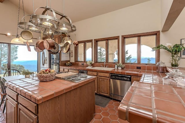 kitchen featuring a center island, tile countertops, stainless steel appliances, and sink