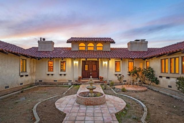 back house at dusk featuring a patio