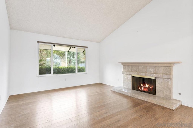 unfurnished living room featuring a textured ceiling, a fireplace, lofted ceiling, and hardwood / wood-style flooring