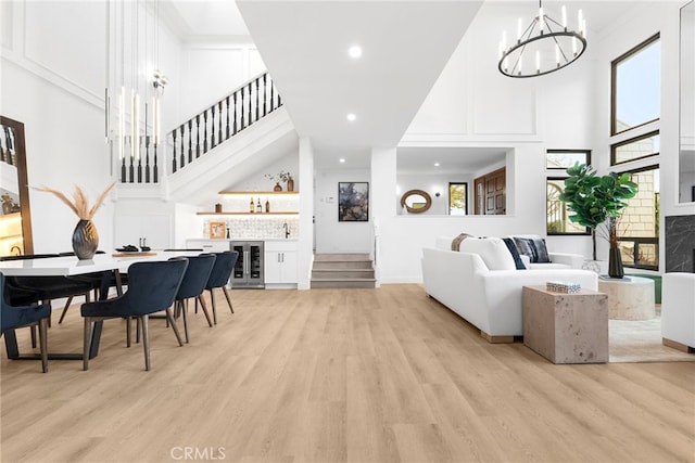 living room featuring wine cooler, indoor bar, a high ceiling, and light wood-type flooring