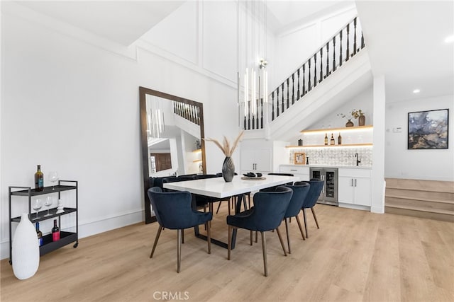 dining area with beverage cooler, light hardwood / wood-style floors, and bar