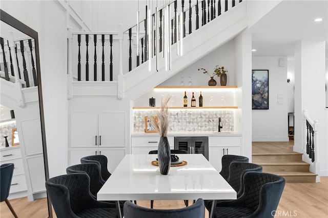 dining room with beverage cooler, light hardwood / wood-style floors, and wet bar