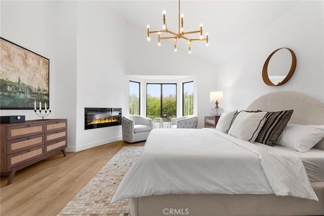 bedroom with light wood-type flooring, high vaulted ceiling, and an inviting chandelier