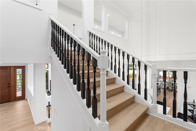 staircase with hardwood / wood-style flooring and a high ceiling