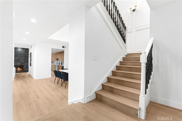 staircase with hardwood / wood-style floors and a high end fireplace