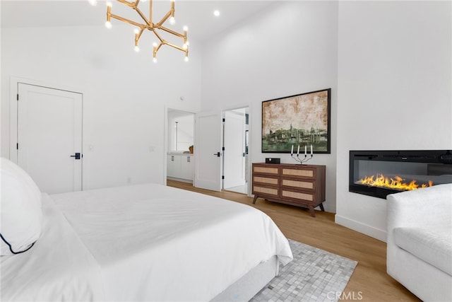 bedroom with light wood-type flooring, high vaulted ceiling, and a chandelier