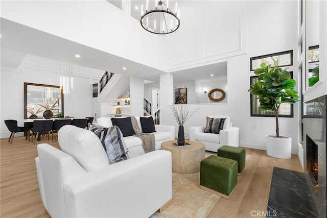 living room with light wood-type flooring, a high ceiling, and an inviting chandelier