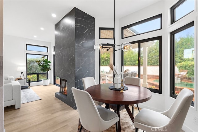 dining room with a fireplace, light hardwood / wood-style flooring, tile walls, and a healthy amount of sunlight