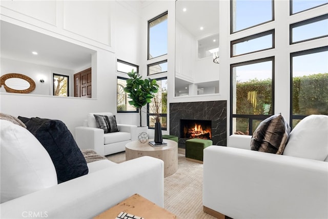 carpeted living room with a high end fireplace and a towering ceiling