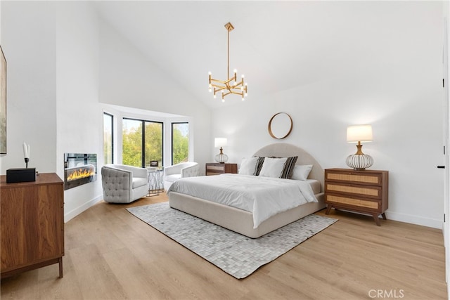 bedroom with light wood-type flooring, high vaulted ceiling, and a chandelier