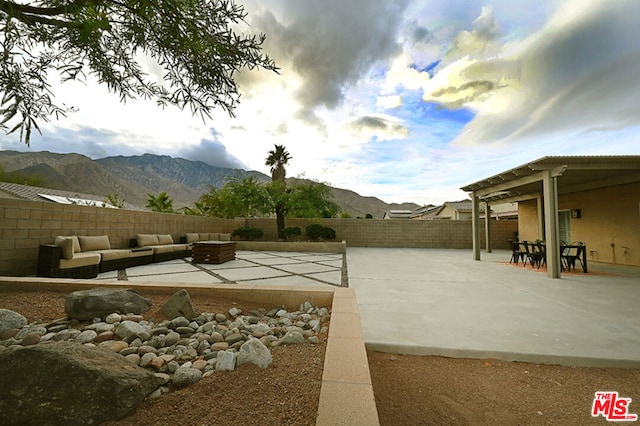 exterior space with a mountain view, a patio, and an outdoor living space with a fire pit