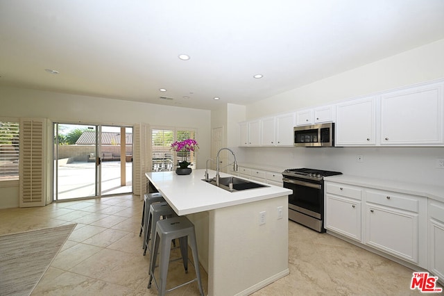 kitchen featuring white cabinets, stainless steel appliances, a kitchen island with sink, and sink