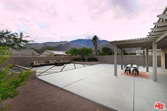 patio terrace at dusk with a mountain view, a pergola, and an outdoor hangout area