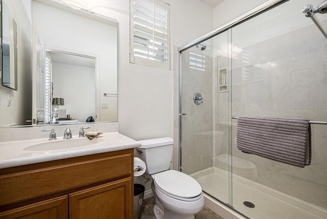 bathroom featuring a shower with shower door, toilet, and vanity